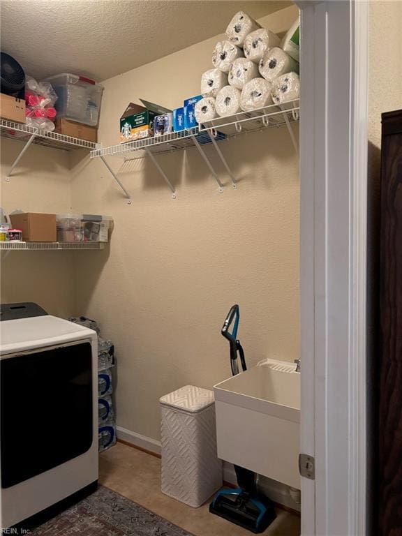 clothes washing area with washer / clothes dryer, sink, and a textured ceiling