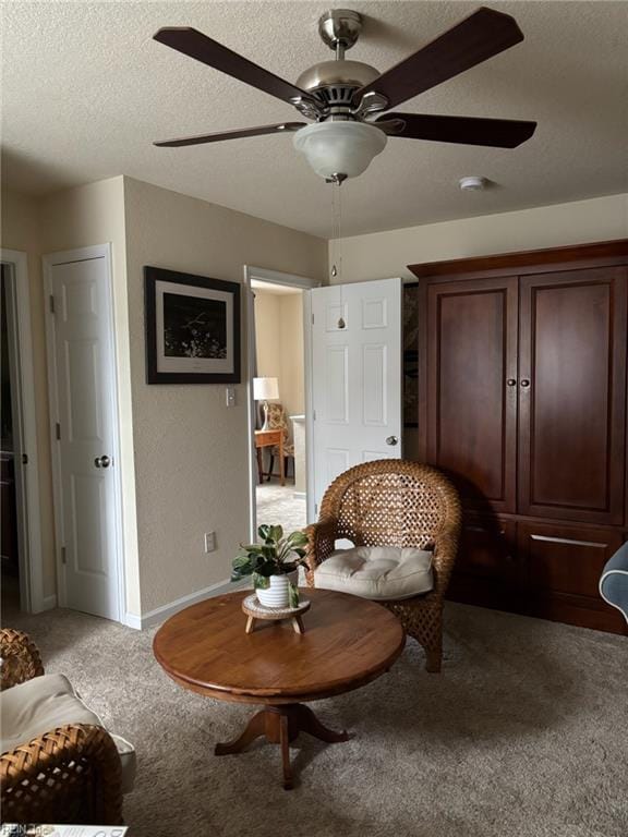 living area with ceiling fan, carpet floors, and a textured ceiling