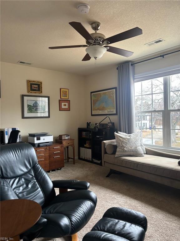 living room featuring ceiling fan, carpet floors, and a textured ceiling