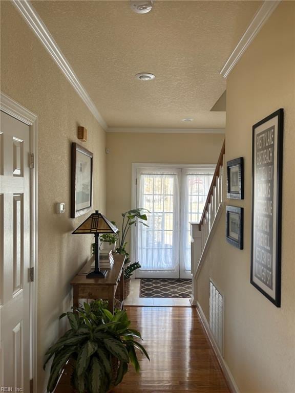 entryway featuring hardwood / wood-style floors, ornamental molding, and a textured ceiling