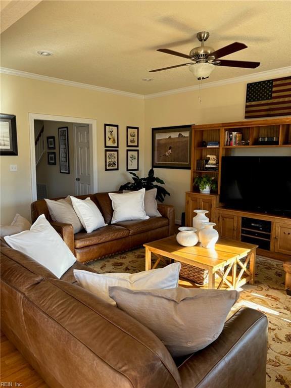 living room with hardwood / wood-style floors, ornamental molding, and ceiling fan