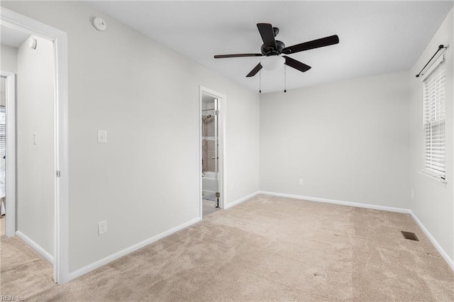 unfurnished bedroom featuring light colored carpet, ceiling fan, and ensuite bathroom