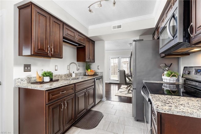 kitchen with sink, ornamental molding, dark brown cabinetry, stainless steel appliances, and light stone countertops