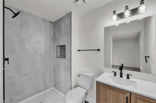 bathroom featuring vanity, toilet, and a tile shower