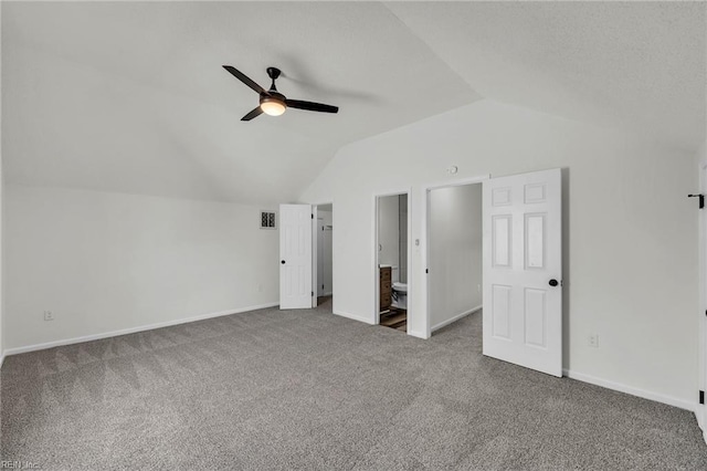 unfurnished bedroom featuring ensuite bathroom, lofted ceiling, carpet floors, and ceiling fan