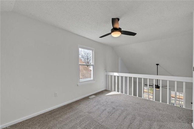 bonus room featuring lofted ceiling, ceiling fan, carpet floors, and a textured ceiling