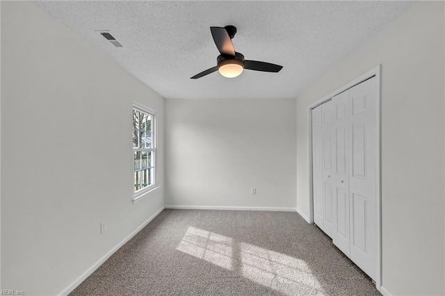 unfurnished bedroom with ceiling fan, carpet floors, a closet, and a textured ceiling