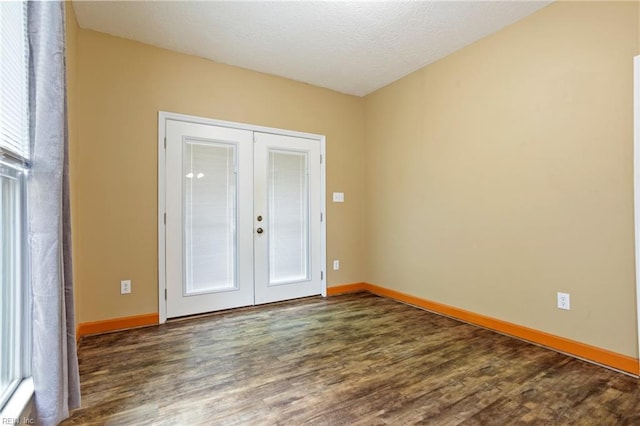 empty room with dark hardwood / wood-style floors, a textured ceiling, and french doors