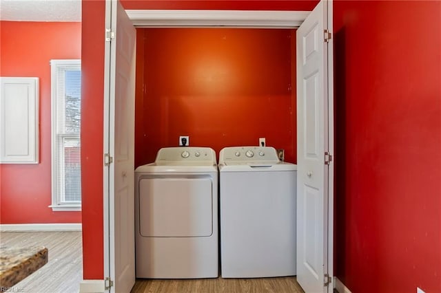 washroom with washing machine and clothes dryer and light wood-type flooring