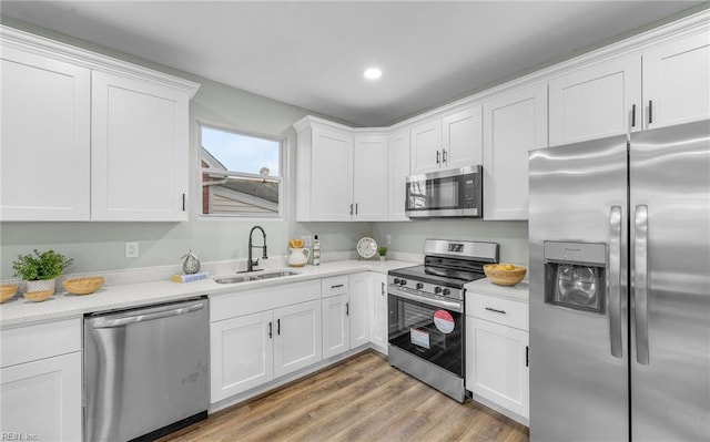 kitchen featuring a sink, white cabinetry, light wood-style floors, light countertops, and appliances with stainless steel finishes