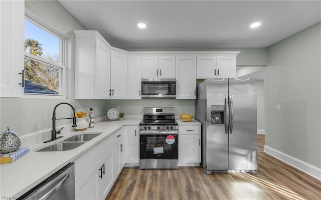 kitchen featuring sink, white cabinets, stainless steel appliances, light stone countertops, and dark wood-type flooring