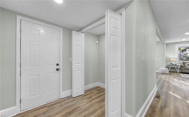 hallway with visible vents, baseboards, and wood finished floors