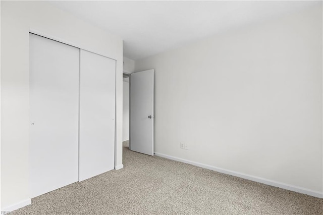 unfurnished bedroom with light colored carpet and a closet