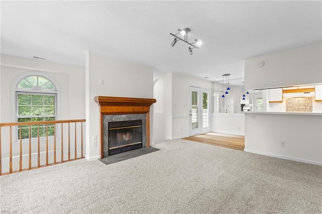 unfurnished living room featuring a fireplace, light carpet, and rail lighting