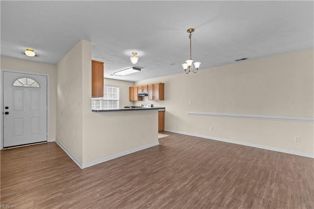 kitchen with hanging light fixtures, wood-type flooring, kitchen peninsula, and a chandelier