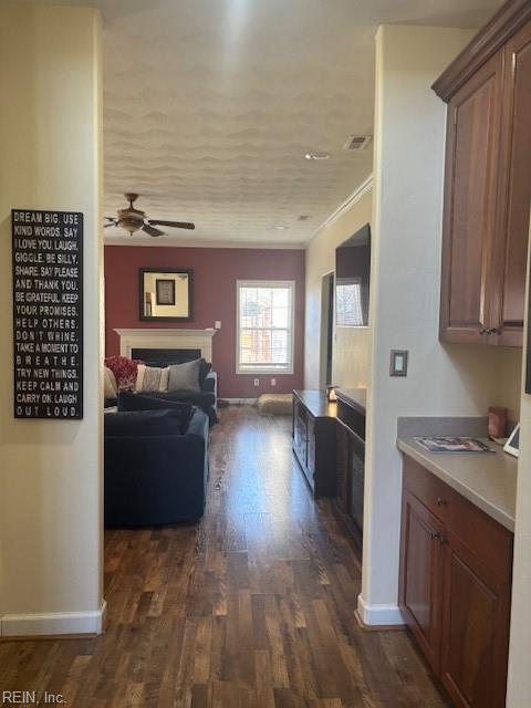 interior space featuring dark hardwood / wood-style flooring, ornamental molding, and ceiling fan