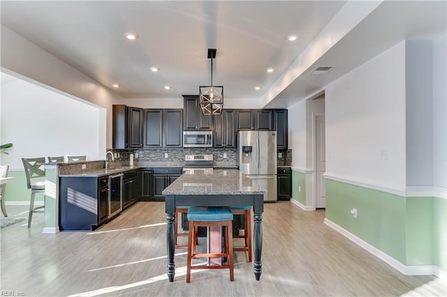 kitchen with pendant lighting, sink, stainless steel appliances, and a kitchen island