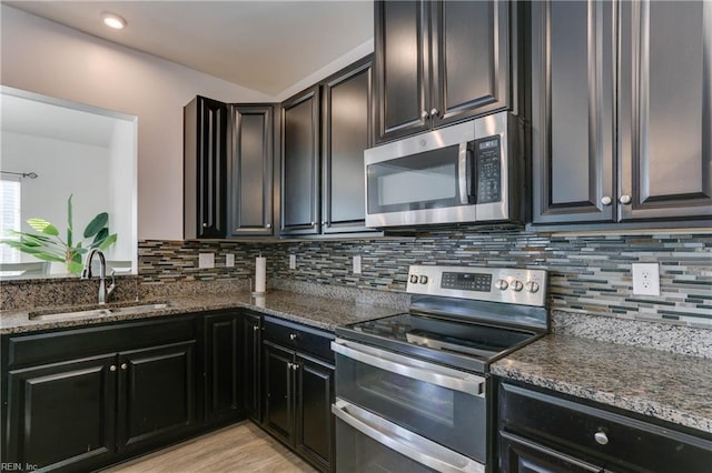 kitchen with dark stone countertops, sink, decorative backsplash, and appliances with stainless steel finishes