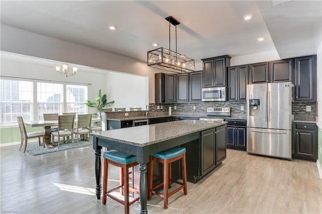 kitchen with decorative light fixtures, a kitchen breakfast bar, decorative backsplash, a center island, and stainless steel appliances