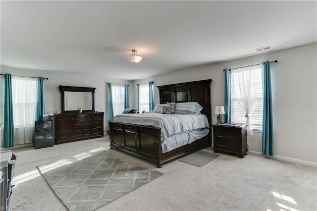 bedroom featuring light colored carpet and multiple windows