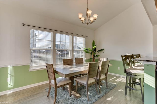 dining space with vaulted ceiling, an inviting chandelier, and light hardwood / wood-style floors