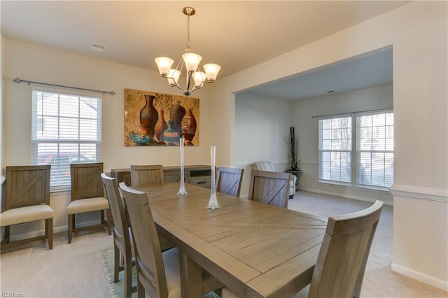 carpeted dining area with a chandelier