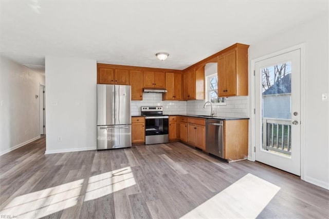 kitchen featuring tasteful backsplash, sink, light wood-type flooring, and appliances with stainless steel finishes