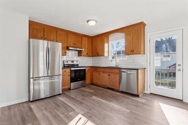 kitchen with sink, backsplash, light wood-type flooring, and appliances with stainless steel finishes