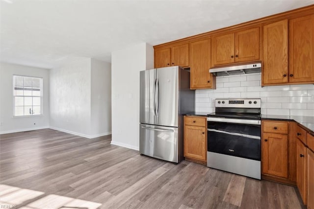 kitchen with tasteful backsplash, stainless steel appliances, and light wood-type flooring