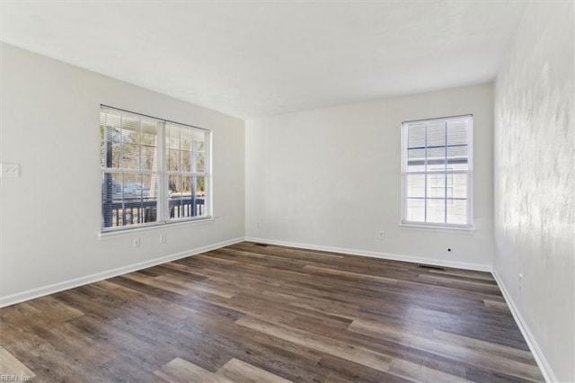 empty room featuring a healthy amount of sunlight and dark hardwood / wood-style floors