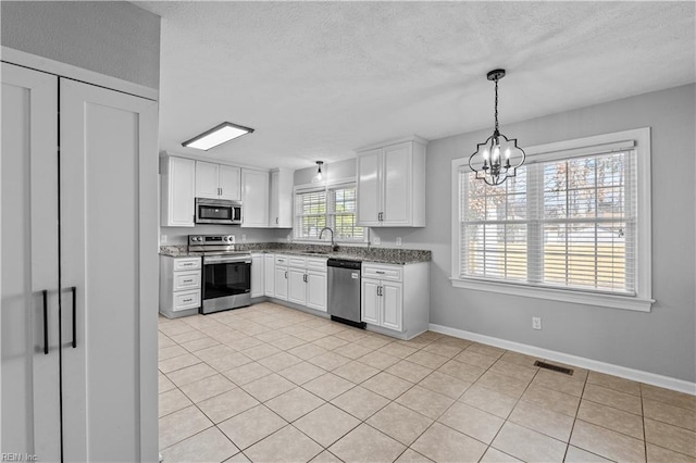 kitchen with sink, decorative light fixtures, appliances with stainless steel finishes, a notable chandelier, and white cabinets