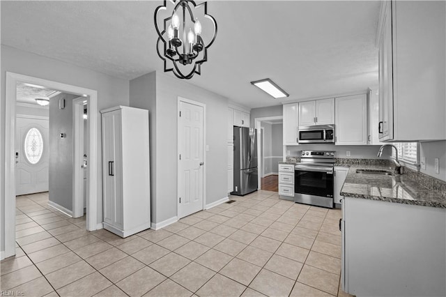 kitchen with decorative light fixtures, sink, white cabinets, light tile patterned floors, and stainless steel appliances