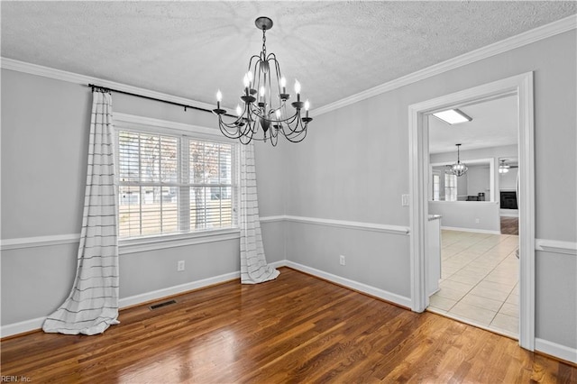 unfurnished room with hardwood / wood-style flooring, crown molding, and a chandelier