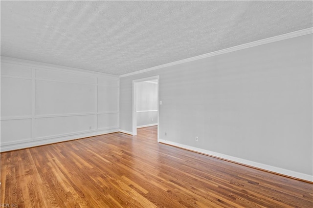 spare room featuring crown molding, a textured ceiling, and hardwood / wood-style flooring