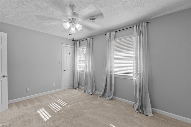 unfurnished room with light colored carpet, a textured ceiling, and ceiling fan