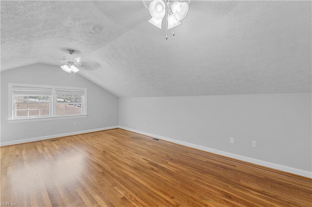 bonus room featuring hardwood / wood-style flooring, ceiling fan, lofted ceiling, and a textured ceiling