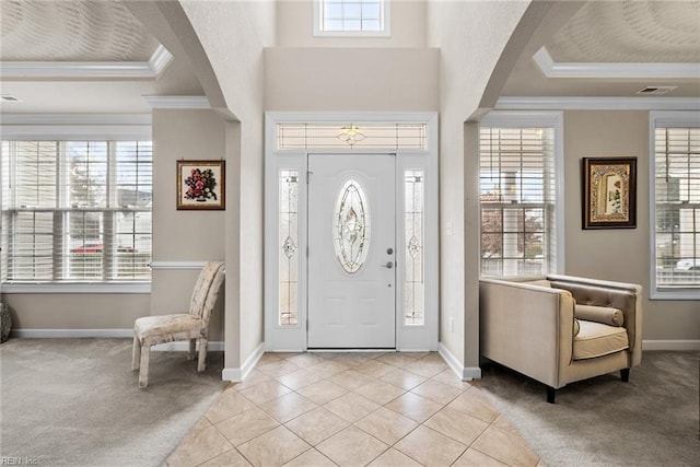 entrance foyer featuring a tray ceiling, crown molding, light colored carpet, and a towering ceiling