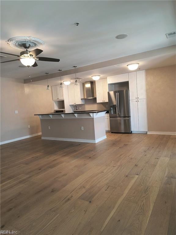 kitchen featuring pendant lighting, wood-type flooring, white cabinets, ceiling fan, and stainless steel refrigerator with ice dispenser