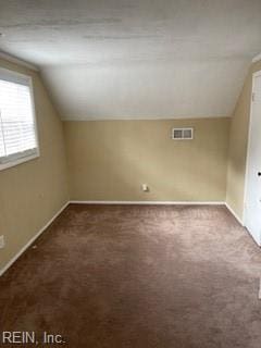 bonus room with vaulted ceiling and dark carpet