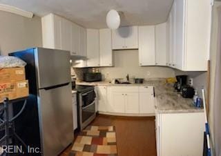 kitchen featuring white cabinetry, light stone countertops, stainless steel appliances, and sink