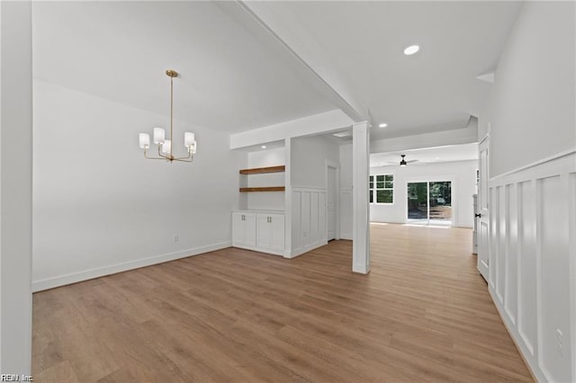 unfurnished living room with ceiling fan with notable chandelier and light wood-type flooring