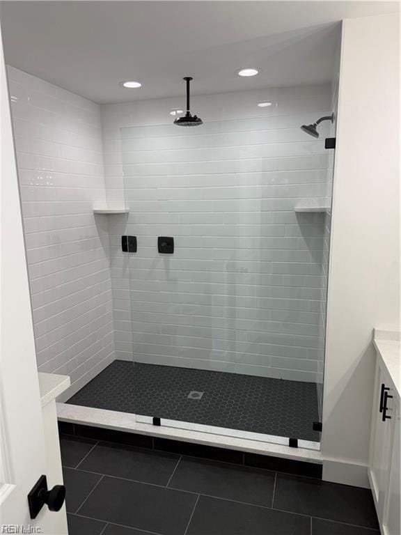 bathroom featuring a tile shower, vanity, and tile patterned floors