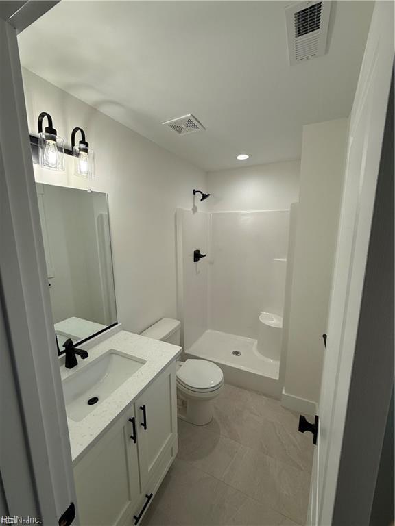 bathroom with tile patterned flooring, a shower, vanity, and toilet