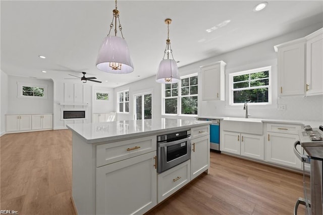 kitchen with decorative light fixtures, stainless steel appliances, white cabinets, and a kitchen island