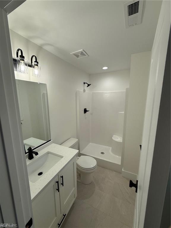 bathroom featuring vanity, a shower, and toilet