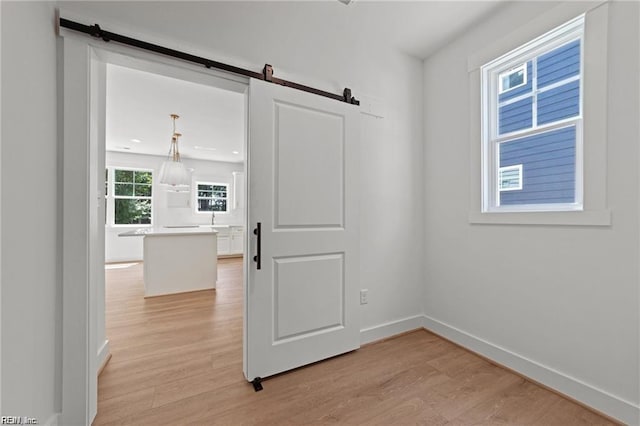 unfurnished room featuring a barn door and light wood-type flooring