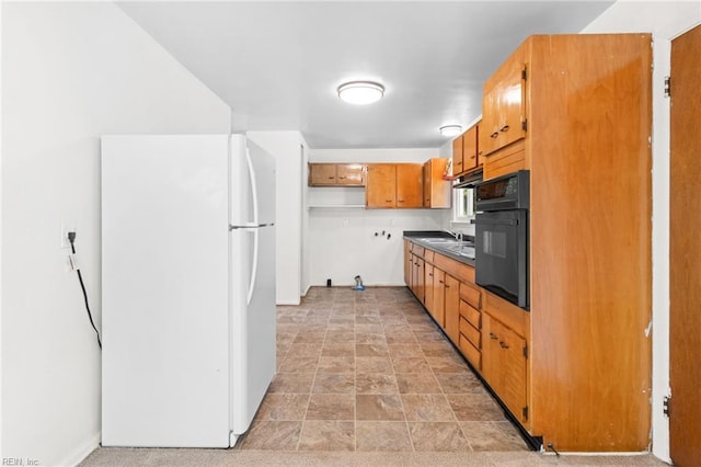 kitchen featuring sink, black oven, and white refrigerator