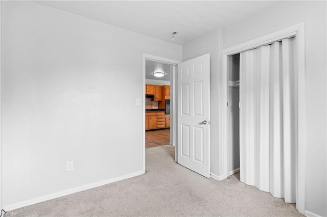 unfurnished bedroom with light colored carpet and a closet