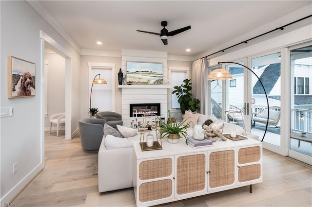 living room with a large fireplace, ceiling fan, and light hardwood / wood-style flooring