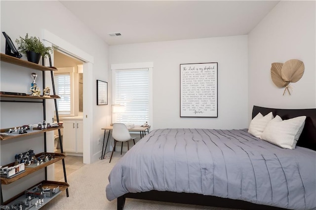 bedroom featuring light colored carpet and connected bathroom